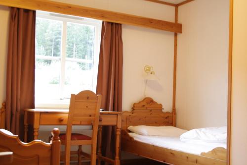 1 dormitorio con 2 camas, escritorio y ventana en Dovreskogen Gjestegård AS en Dovreskogen
