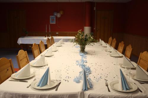 a long table with a white table cloth and blue napkins at Dovreskogen Gjestegård AS in Dovreskogen