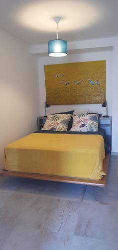 um quarto com uma cama amarela com pássaros na parede em Vue de rêve em Calcatoggio