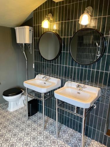 a bathroom with two sinks and a toilet and mirrors at No.123 The Old Post House in Scalby