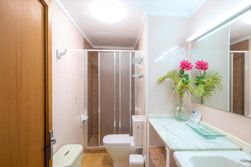 een badkamer met een toilet en een vaas met bloemen op een aanrecht bij Madona - Es Puig in Búger