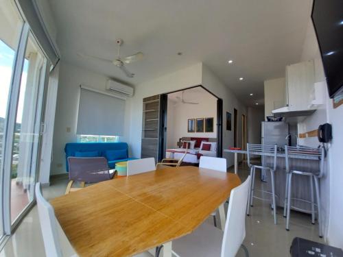 a dining room and kitchen with a wooden table and chairs at Terrazas Tayrona Travelers Apartamentos y Suites in Santa Marta