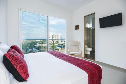 a bedroom with a white bed and a large window at Terrazas Tayrona Travelers Apartamentos y Suites in Santa Marta