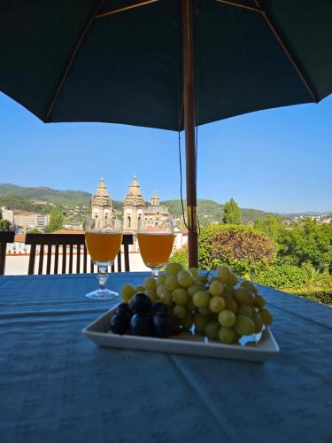 a plate of fruit on a table with two glasses of wine at Casa das Acácias in Cabeceiras de Basto