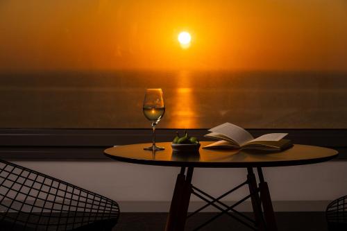 a table with a glass of wine and an open book at Mare Dei Suites Hotel Ionian Resort in Skafidia
