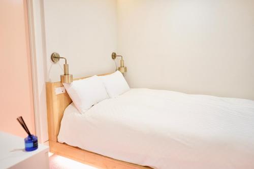 a white bed with two lamps on top of it at 东京上野超级中心 设计师房间Yaoa 上野公园3分钟 车站1分钟 超级繁华 免费wifi 戴森吹风 in Tokyo