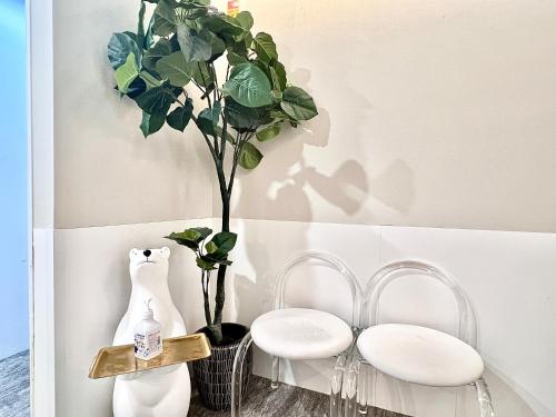 a room with two white chairs and a potted plant at 东京上野超级中心 设计师房间Yaoa 上野公园3分钟 车站1分钟 超级繁华 免费wifi 戴森吹风 in Tokyo