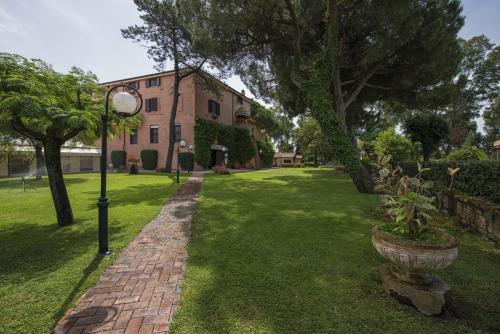 a brick pathway leading to a building with a plant in a pot at La Pineta Dei Liberti in Lido dei Pini