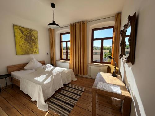 a bedroom with a white bed and two windows at Künstlerzimmer im Kulturhaus Häselburg in Gera