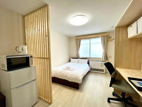 a small room with a bed and a television and a desk at NORTH LIVE 2 in Ōdōri