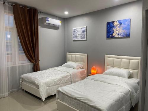 een slaapkamer met 2 bedden en een raam bij คาเฟ่ เดอ แจ่วบอง รูมแอนด์เซอร์วิส in Khon Kaen