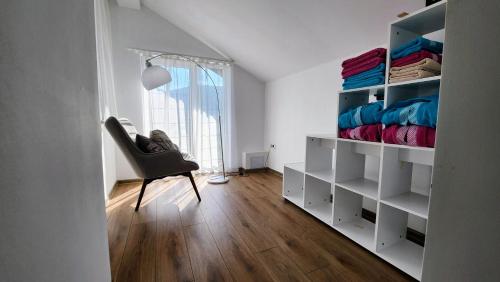 1 dormitorio con estanterías blancas y silla en Вила с басейн и джакузи, en Goranovtsi