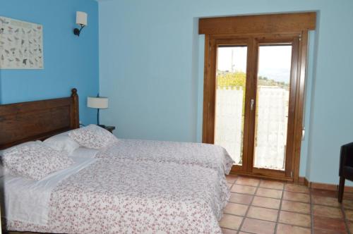 a blue bedroom with a bed and a sliding glass door at Las Abadías in San Felices