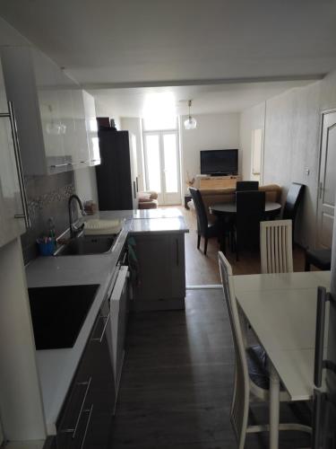 cocina con fregadero y mesa con sillas en Appartement 4 chambres, 5 lits et un canapé convertible en Annonay