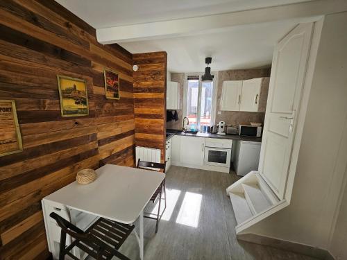 cocina con paredes de madera, mesa blanca y sillas en Entre 2 mers, en Le Tréport