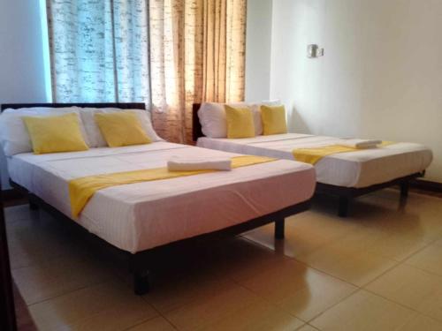 two beds in a room with yellow pillows at Royal Apartments in Mombasa