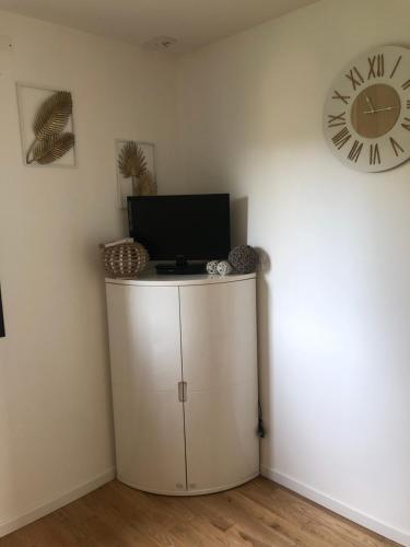 Zimmer mit einem TV und einer Uhr an der Wand in der Unterkunft Chambre dans maison d'architecte in Cherbourg en Cotentin