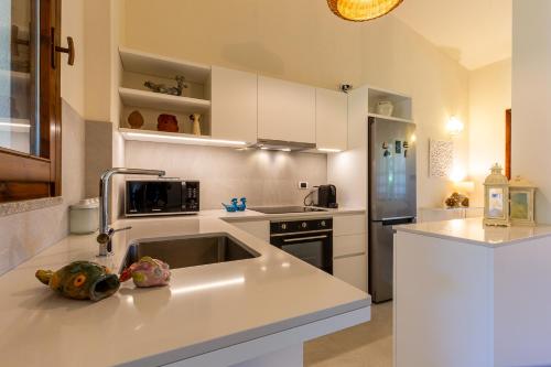 a white kitchen with a sink and a refrigerator at Patio Relax - 200m from beach - Villasimius in Notteri