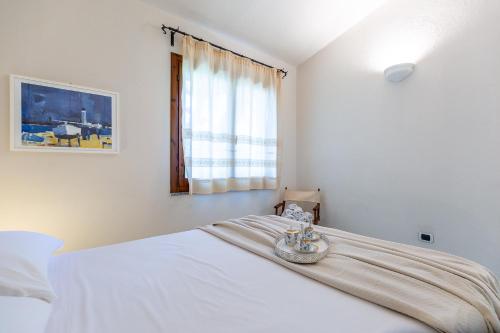 a bedroom with a large white bed with a window at Patio Relax - 200m from beach - Villasimius in Notteri