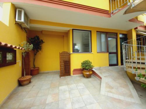 a yellow house with potted plants on a patio at Casa Cristina in Quartu SantʼElena