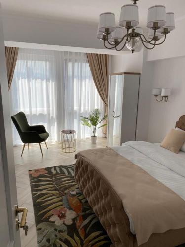 a bedroom with a bed and a chair and a window at Elite Apartment in Sibiu