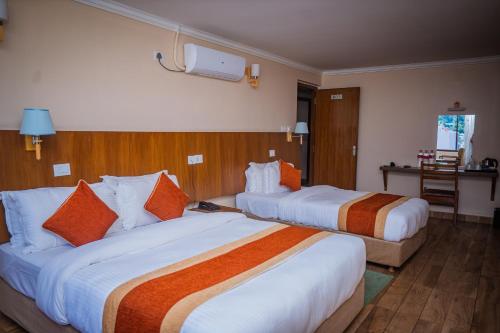 a hotel room with two beds with orange and white pillows at Hotel Fewa Camp in Pokhara