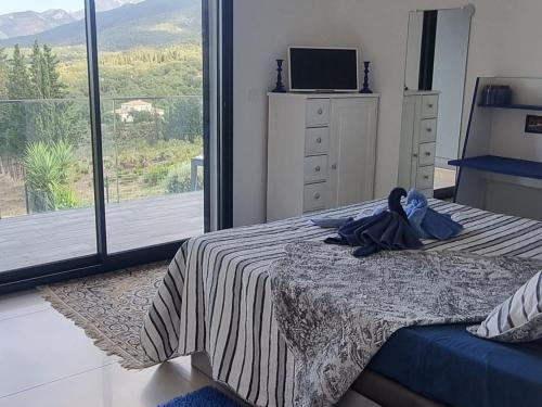 une chambre avec un lit et une grande fenêtre dans l'établissement Chambre de luxe, spa, piscine, entre mer et montagne, à Villelongue-dels-Monts