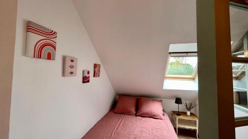 um pequeno quarto com uma cama rosa e uma janela em Le Petit Refuge par Your Sweet Loc em Le Meux