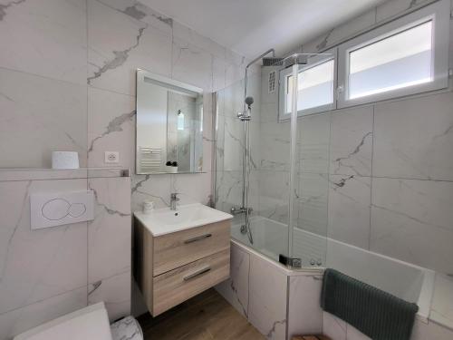 a white bathroom with a sink and a shower at Le Prasino - Paisible appartement proche RER in Massy