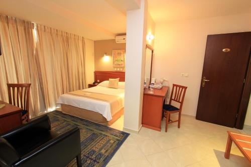ピレウスにあるトリトン ホテル ピレウスのベッドとリビングルームが備わるホテルルームです。