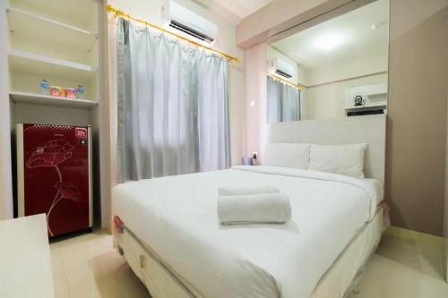um quarto com uma grande cama branca e uma janela em Green Pramuka city Harian by Dea roooms em Jakarta