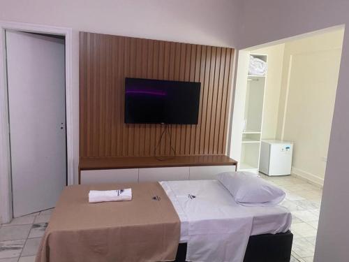 a bedroom with a bed and a flat screen tv at Pousada Sol da Enseada Guarujá Inn - Piscina Aquecida in Guarujá