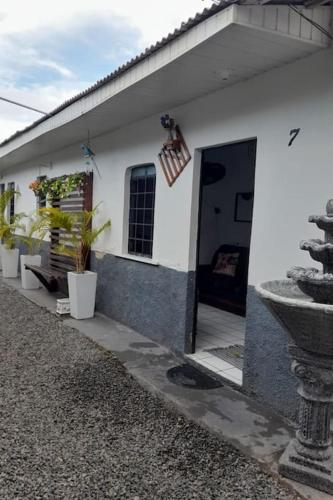 a white house with a door and potted plants at Nômade no Liberdade in Boa Vista