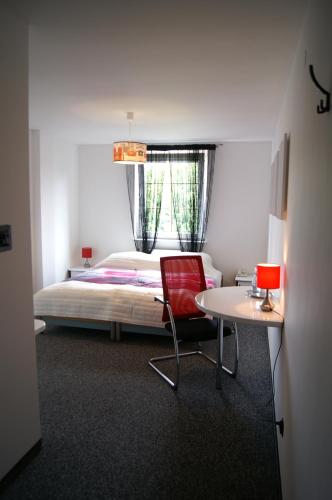 a bedroom with a bed and a red chair and a table at Hotel Restauracja Venus in Moderówka