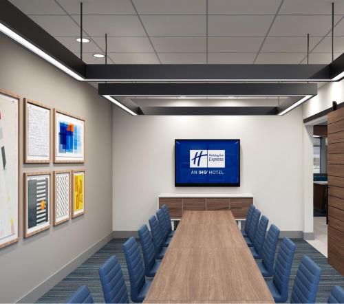 a conference room with a tv and blue chairs at Holiday Inn Express Cape Canaveral by IHG in Cape Canaveral