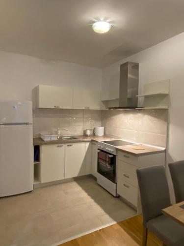uma cozinha com armários brancos e um frigorífico branco em Nikolina em Skopje