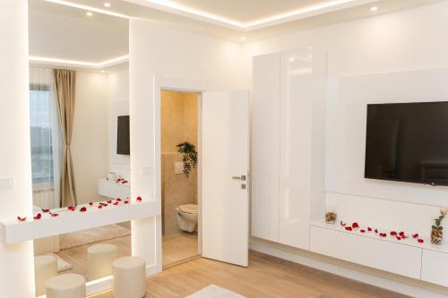 a white bathroom with a toilet and a tv on a wall at SINFONIA LUX in Belgrade
