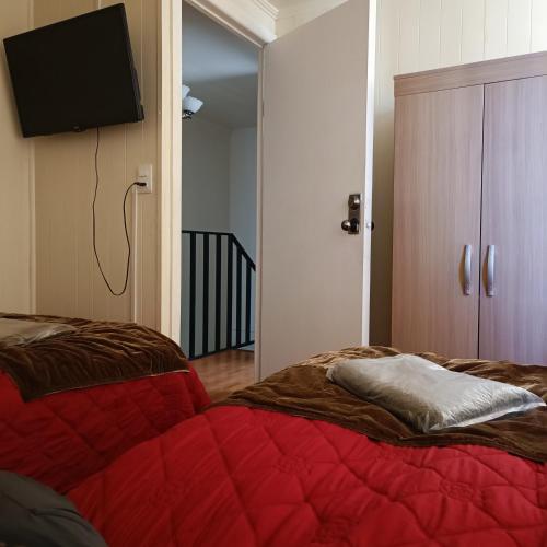 um quarto com uma cama vermelha e uma televisão de ecrã plano em Casa dos dormitorios em Iquique