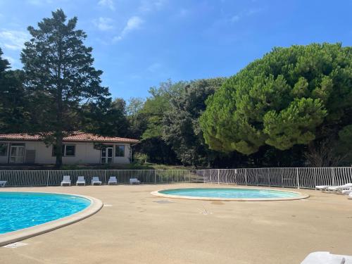 two pools in a yard with chairs and trees at Duplex 3 piscines (1 chauffée/couverte) 300m plage in Les Sables Vignier