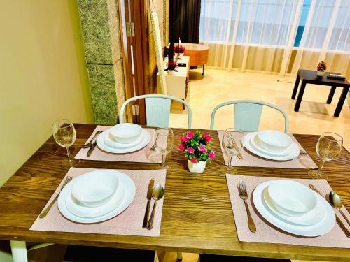 a wooden table with white plates and silverware on it at Vortex Suites KLCC by UNIQUE in Kuala Lumpur