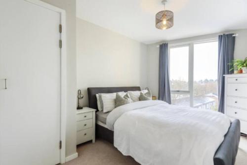 3 Bedroom Penthouse Apartment Central Maidenhead في ميدينهيد: غرفة نوم بيضاء بها سرير ونافذة