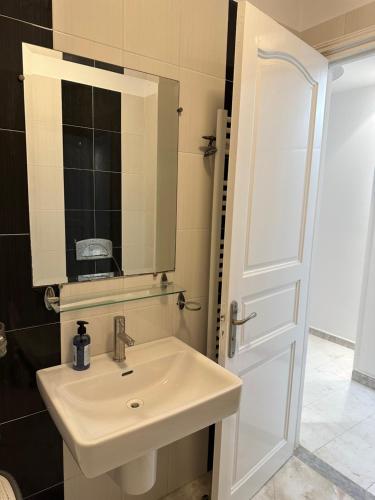 ein Bad mit einem Waschbecken und einem Spiegel in der Unterkunft Appartement haut standing 170 m2 in Tunis