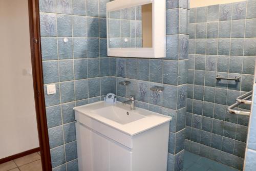 uma casa de banho com um lavatório branco e azulejos azuis em Faatau House 3 bedrooms and big living room em Papeete