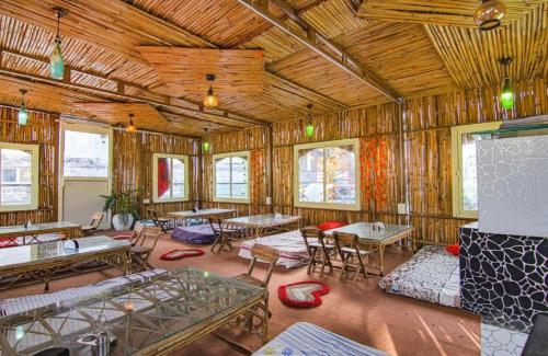 een grote kamer met tafels, stoelen en ramen bij Hotel 4 You - With Open Rooftop Cafe in Rishīkesh
