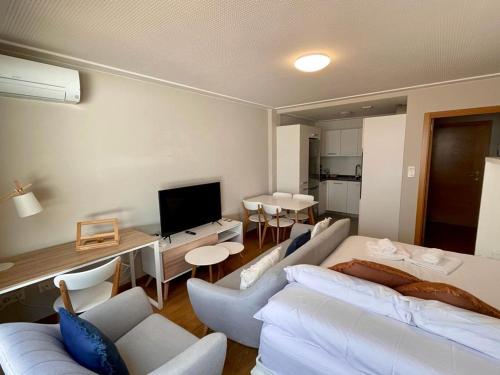 sala de estar con muebles blancos y TV en Estudio céntrico 2 con terraza y parking privado, en Ourense