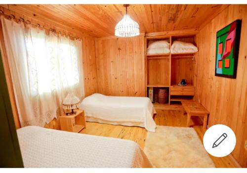 a bedroom with two beds in a wooden cabin at Pousada Villa dos Vinhedos in São Joaquim