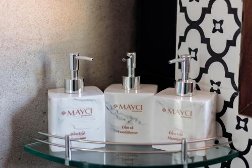 two white soap bottles on a glass shelf in a bathroom at Mayci Boutique Hotel & Restaurant by Amber in Hoi An