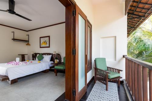 a bedroom with a bed and chairs and a balcony at Mayci Boutique Hotel & Restaurant by Amber in Hoi An
