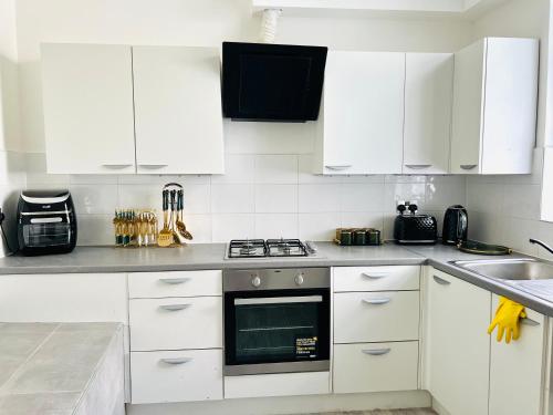 Luxury Morden 4 bedroom Flats which will make you unforgettable في لندن: مطبخ بدولاب بيضاء وفرن علوي موقد