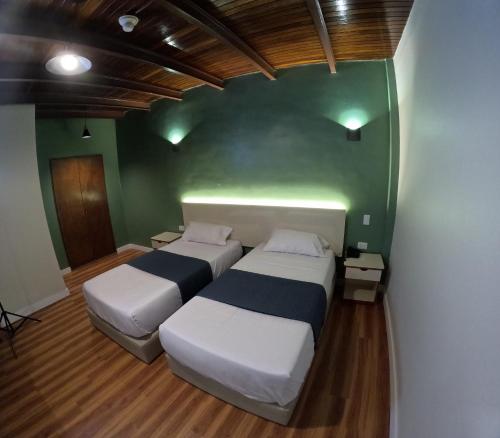 two beds in a room with a green wall at Hotel El Arroyo in Caracas